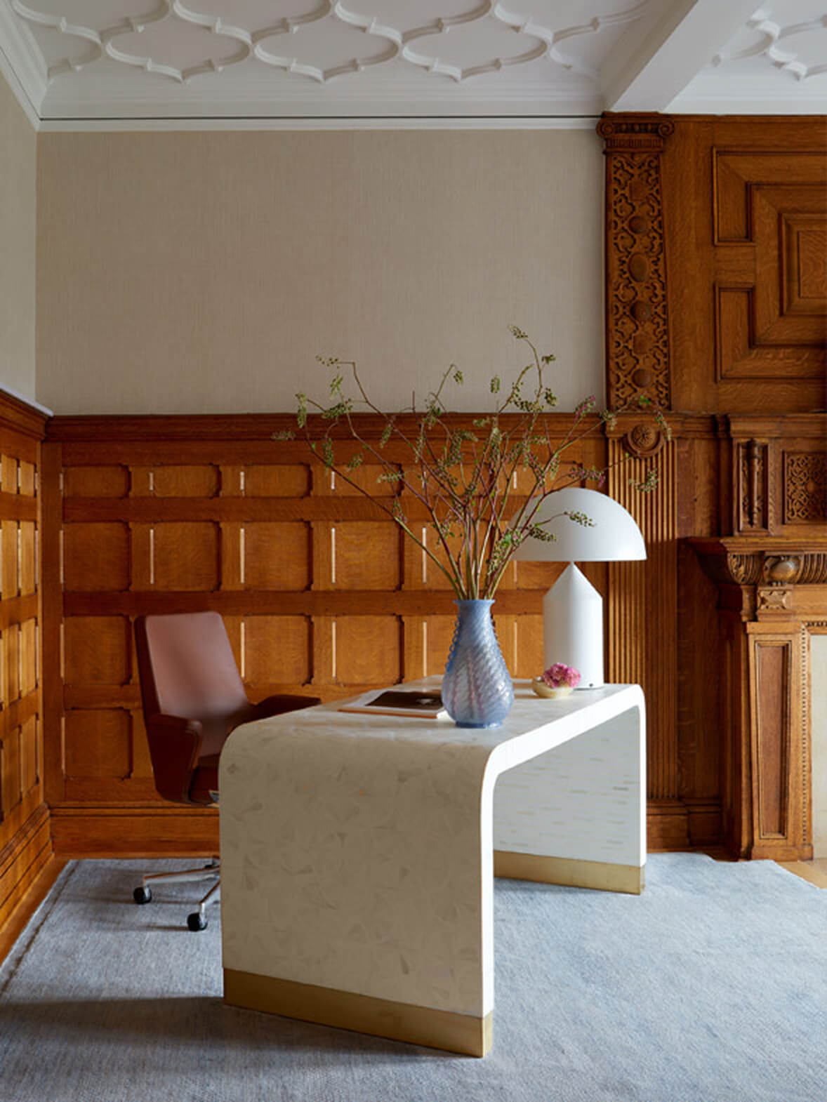 Wine Leather Humanscale Summa chair behind white curved desk in wood paneled executive office