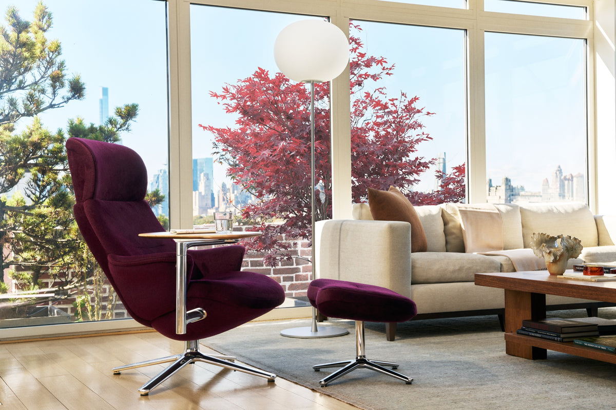 Wine Humanscale Diffrient Lounge chair with matching ottoman and side table in a modern living room with an urban skyline view