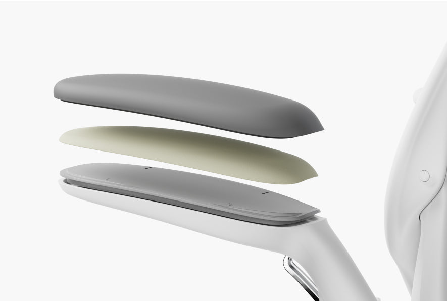 A layered view of Humanscale office chair armrest components, showing the top cushion, internal padding, and supporting base structure in a light grey and white color scheme