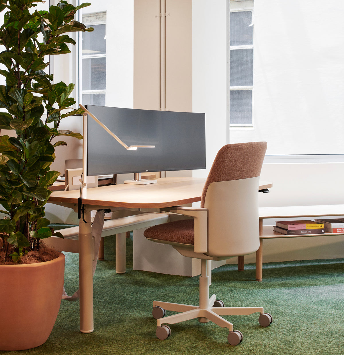 A modern office setup featuring a light wood corner desk with a dark gray monitor, a cream and brown Path office chair.