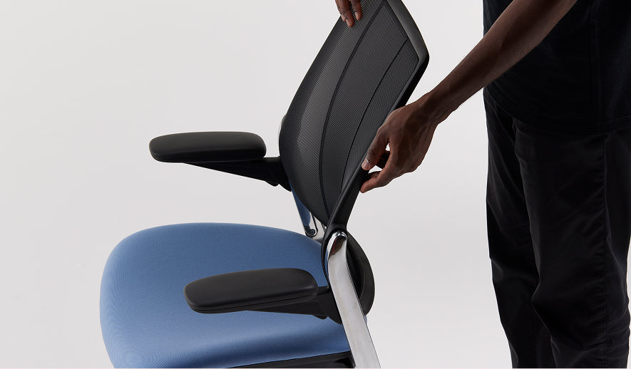 Person adjusting Humanscale Liberty Ocean black mesh chair with Kvadrat upholstery.