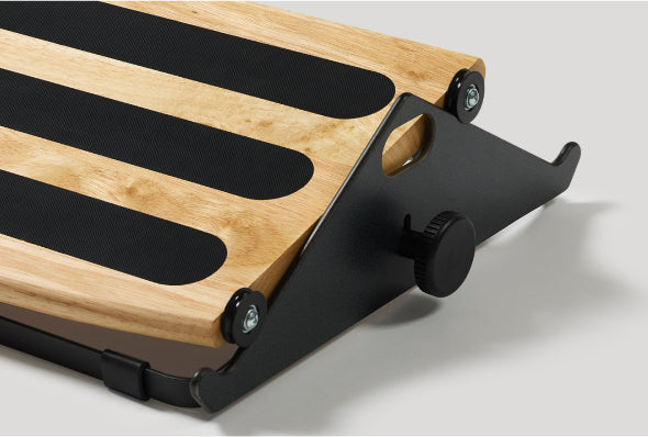 A close-up view of a Humanscale FR300 ergonomic foot rocker featuring a solid wood platform with black non-slip strips and a side knob for height adjustment