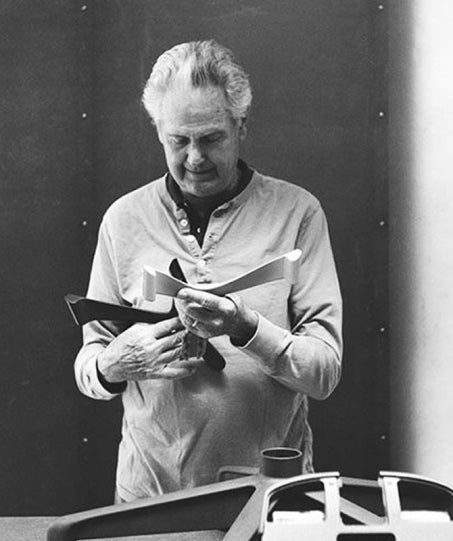 A black and white photo of legendary designer Don Chadwick examining chair frame components, showcasing the meticulous design process behind Humanscale products