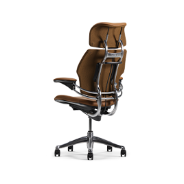 A rear diagonal view of a Humanscale Freedom Ocean chair with headrest, upholstered in premium brown saddle leather with a polished aluminum frame, showcasing the external spine and headrest mechanism against a white background