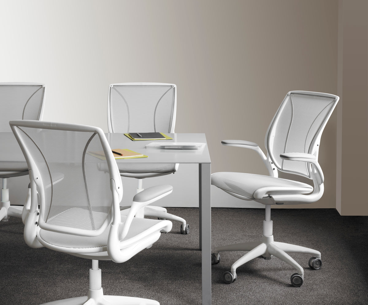 Four Humanscale World Mesh chairs with pinstripe white mesh back and seat and white frames arranged around a gray meeting table