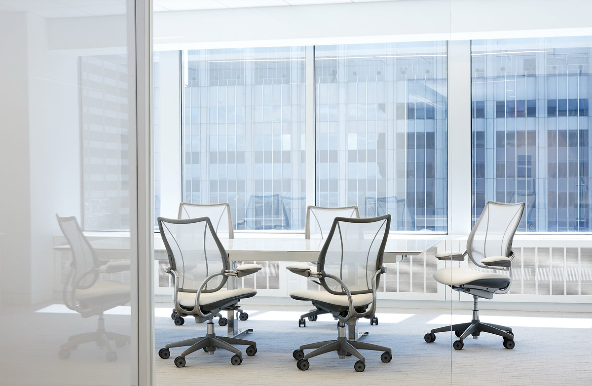 Modern meeting room featuring five Humanscale Liberty task chairs with pinstripe white mesh, white leather seats, and polished aluminum frames around a white table