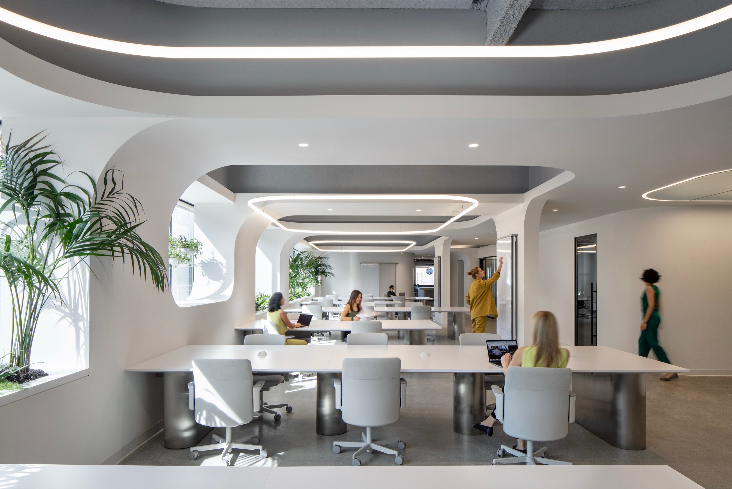 Modern office space with people working at a long table.