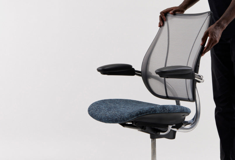 Person adjusting a Humanscale Liberty Ocean task chair featuring pinstripe black mesh and a blue textile seat