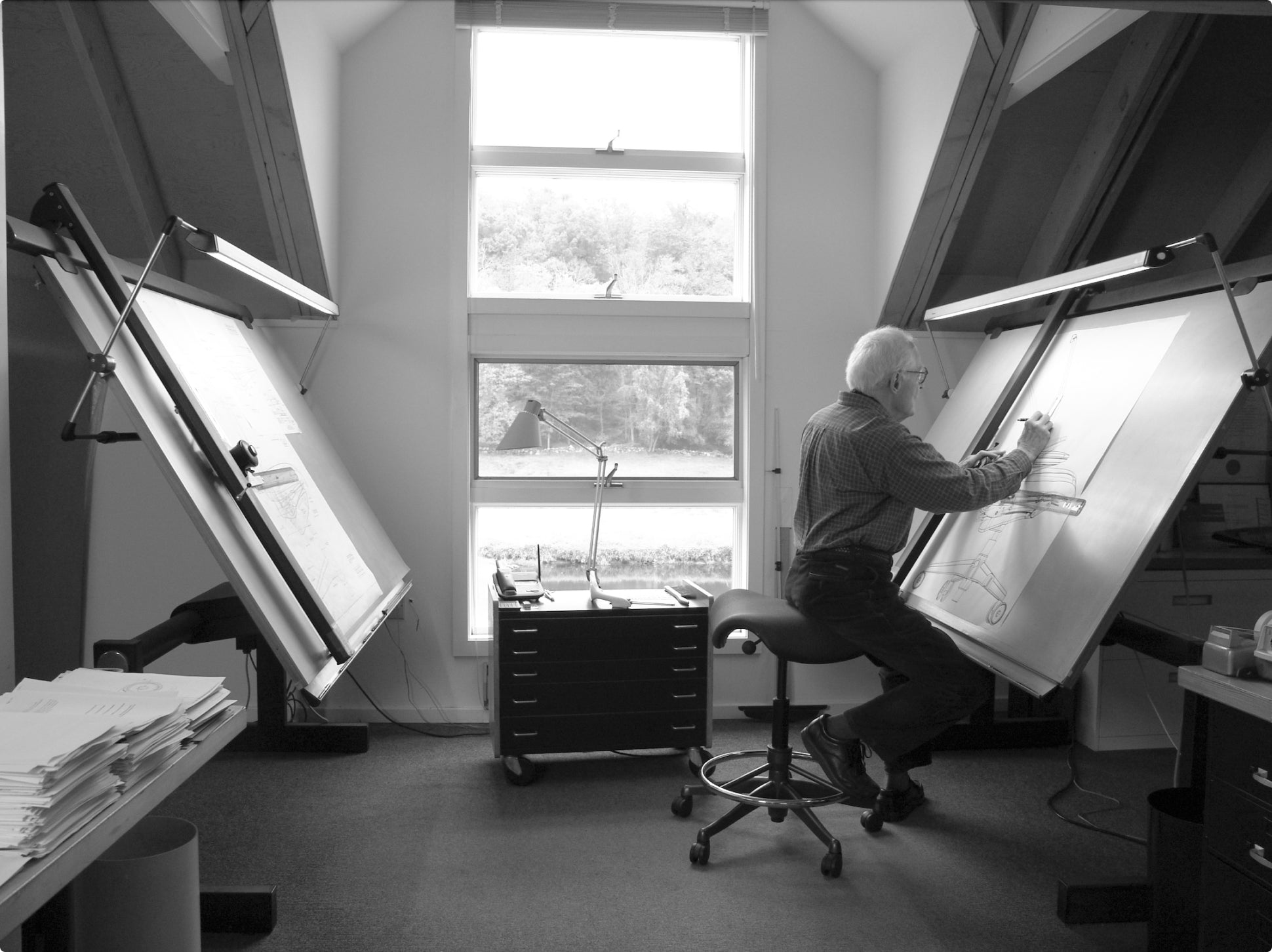Niels Diffrient designing on board while sitting on Humanscale Freedom Saddle Stool ring base