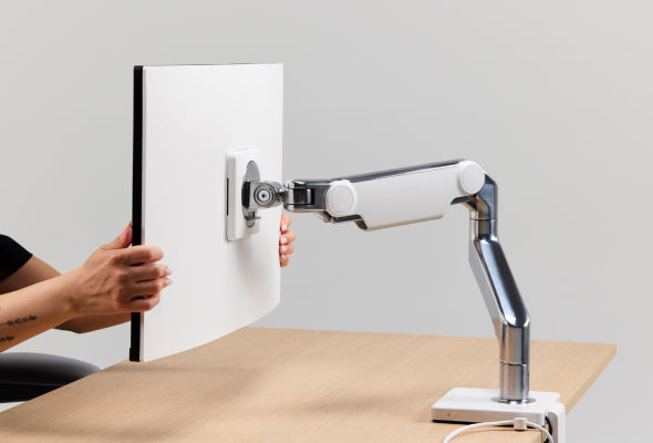 Person adjusting monitor on Humanscale M8 Pro arm with M/Connect 2 docking station.