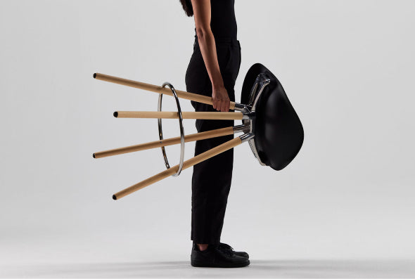 Woman holding Humanscale Sedeo solid maple bar stool with black seat.