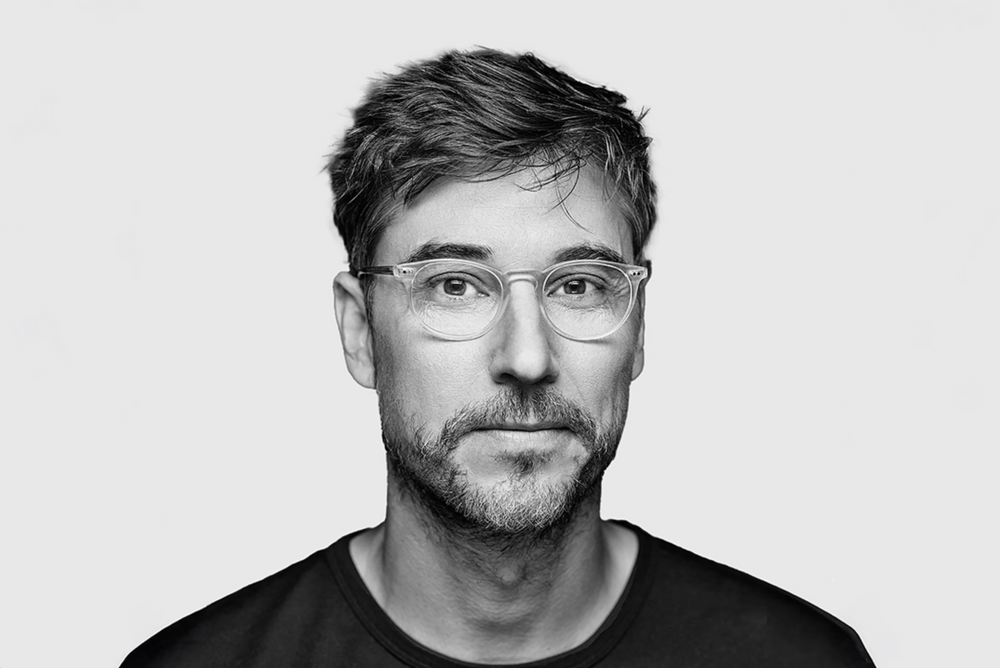 Portrait of Todd Bracher with glasses and short hair on a light gray background