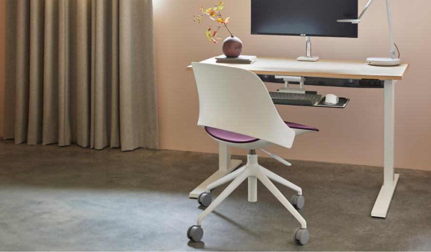 Humanscale Trea white chair with a purple textile cushion at a standing desk